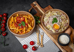 Duo de bols Ô'Feno Gusto : penne sauce tomate et carbonara à l'œuf coulant, dressés sur planche en bois avec tomates cerises