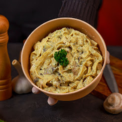 Tagliatelles crémeuses garnies de persil frais servies dans un bol kraft